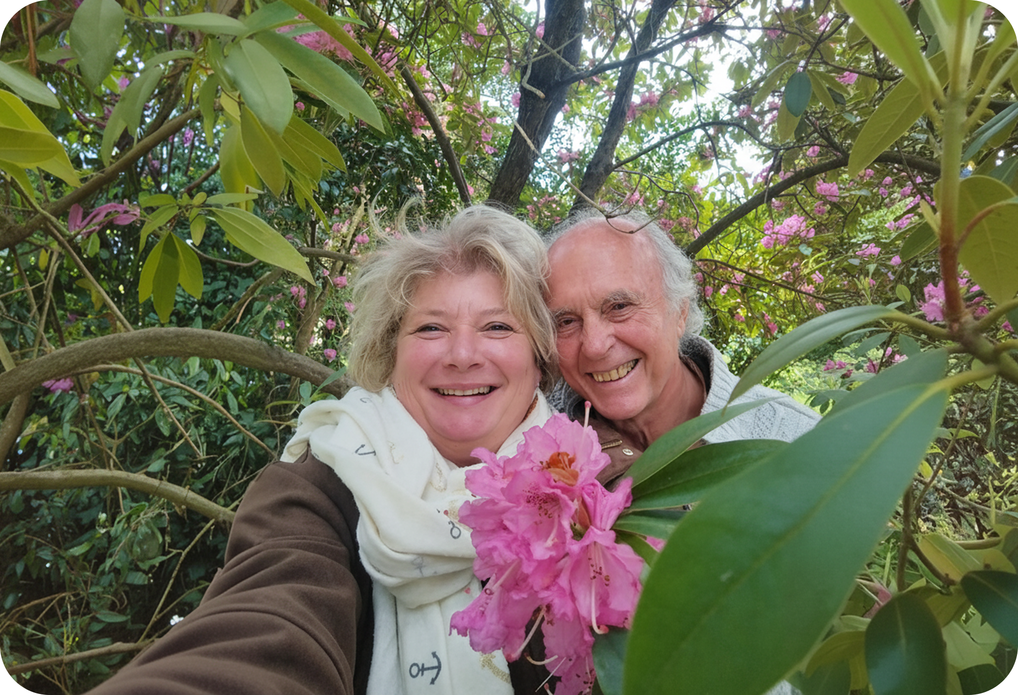 Two people standing among pink flowers and green foliage