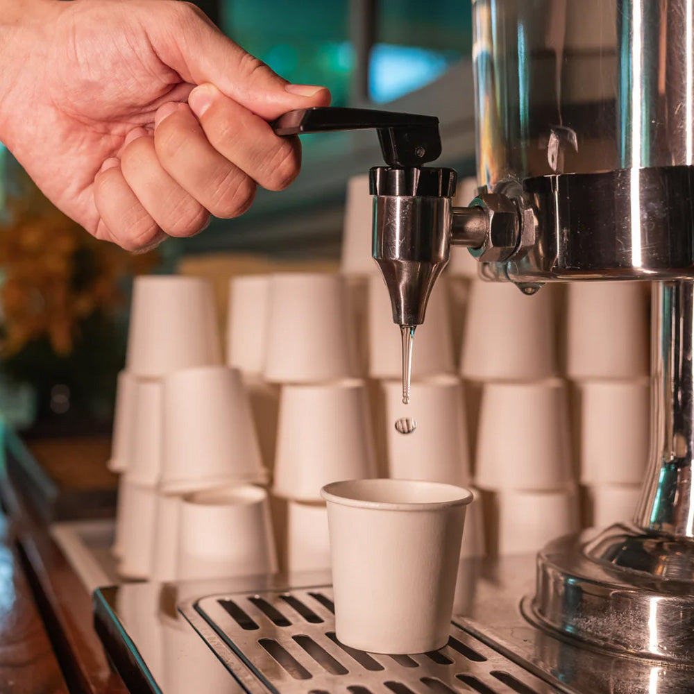 Hand dispensing water into a paper cup, supplements health concept, gym setting
