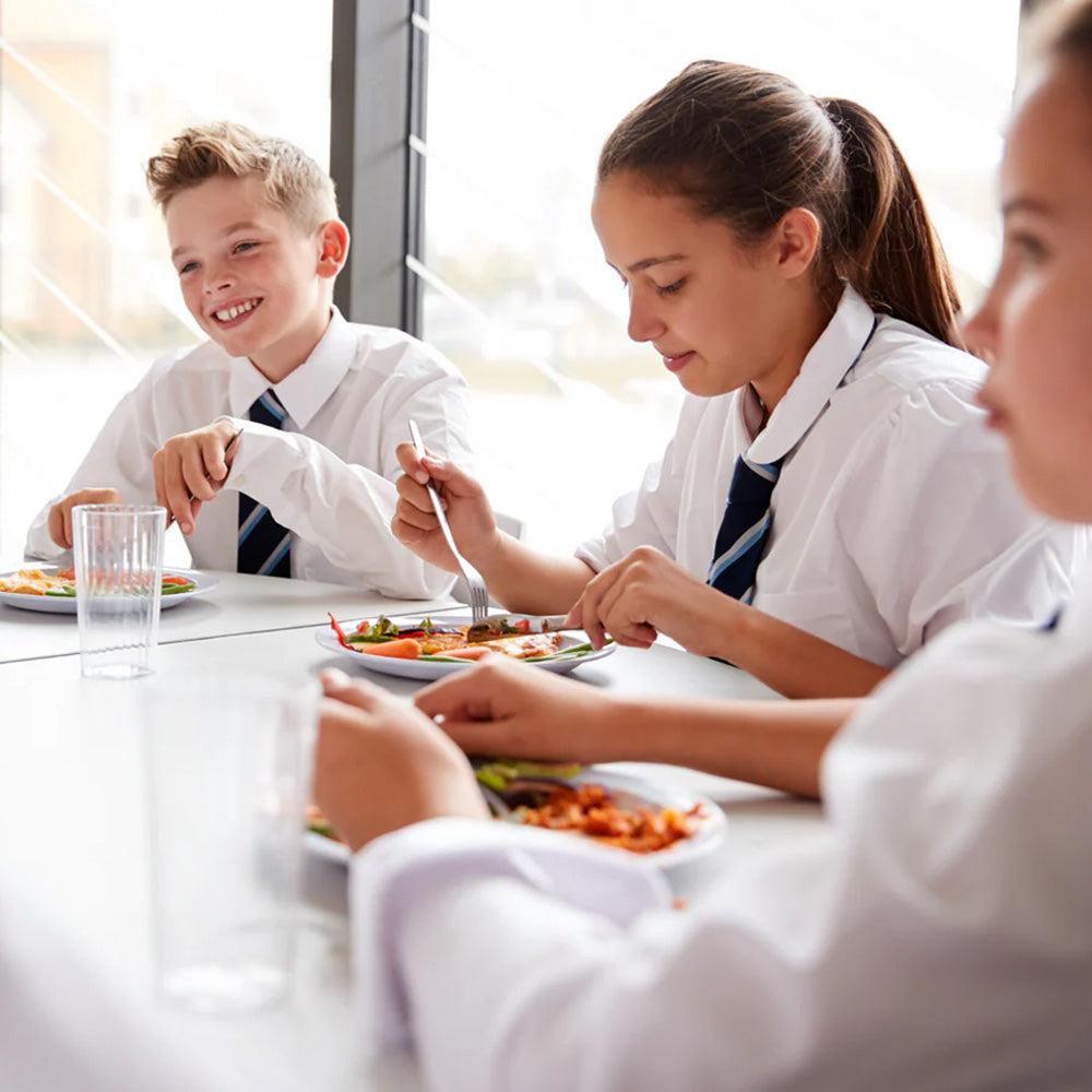 Students in uniforms eating healthy meals at school cafeteria, supplements health focus