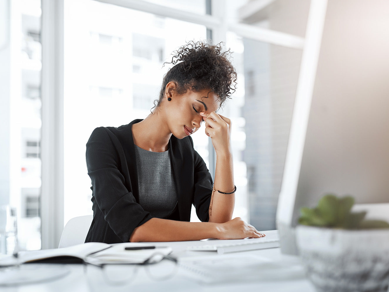 Woman at desk looking fatigued, supplements health, possible stress or tiredness symptoms